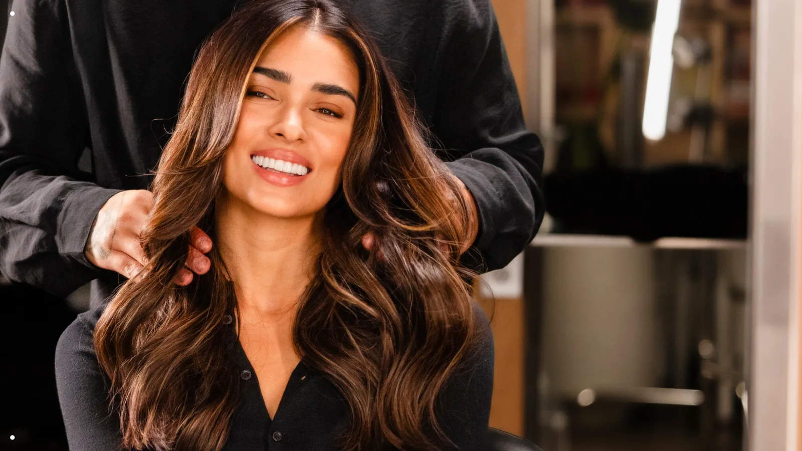 Aveda hair color client with glossy brunette waves in the chair at an Aveda salon